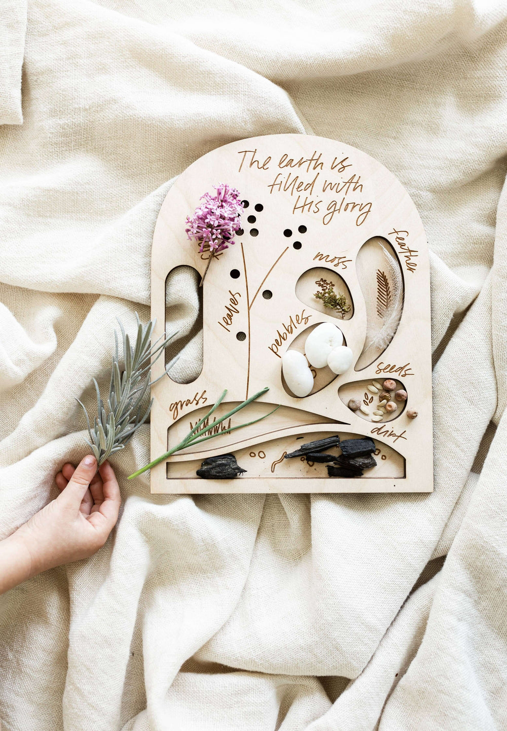 A child holding the eco-friendly Glory Nature Board showcasing natural elements and the phrase 'The earth is filled with His glory'.