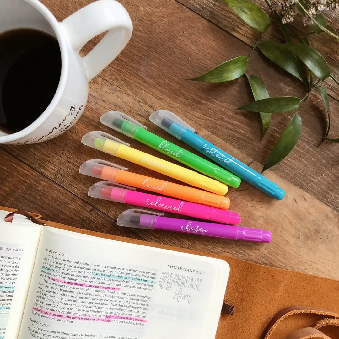 Scented gel highlighters set in vibrant colors laid out beside a coffee cup and an open Bible on a wooden surface.