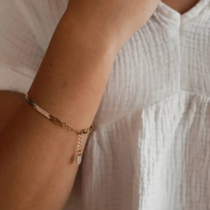Close-up of Steadfast Love Bracelet on wrist, featuring 14kt gold-plated chain and engraved tag.
