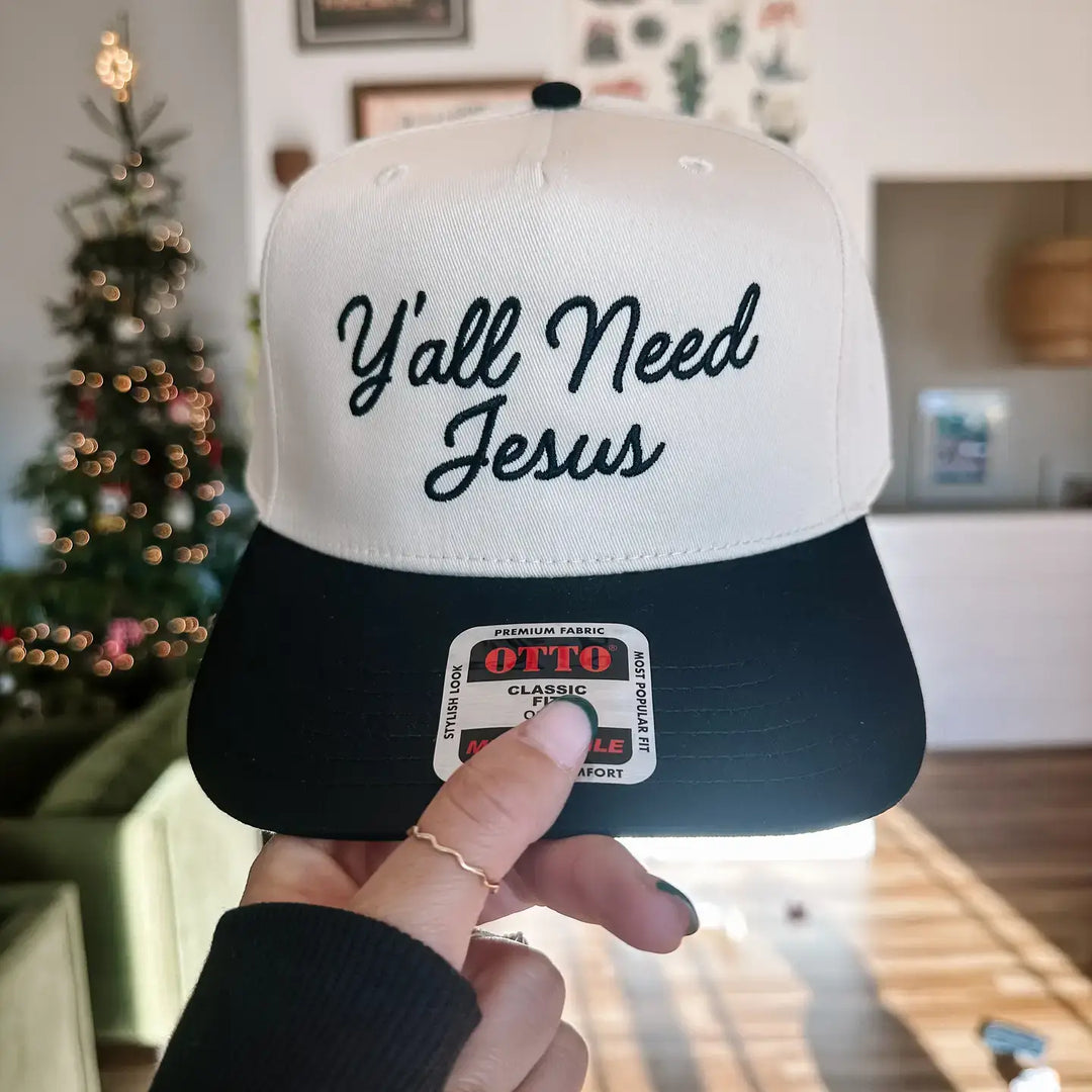 Y'all Need Jesus embroidered hat in black and cream, showcasing modern style and bold faith statement.