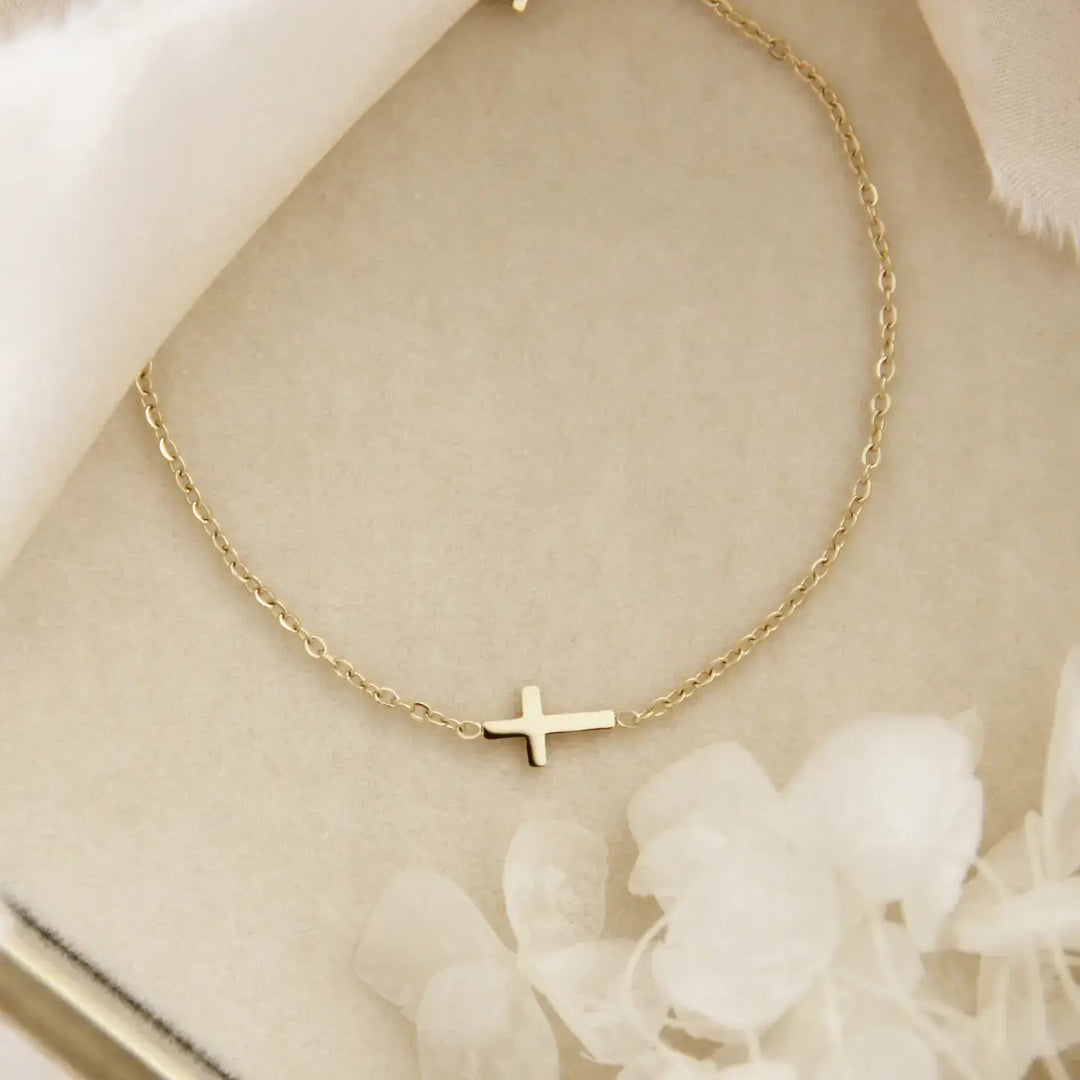 Dainty sideways cross bracelet in 18K gold over surgical steel, elegant faith accessory for daily inspiration.