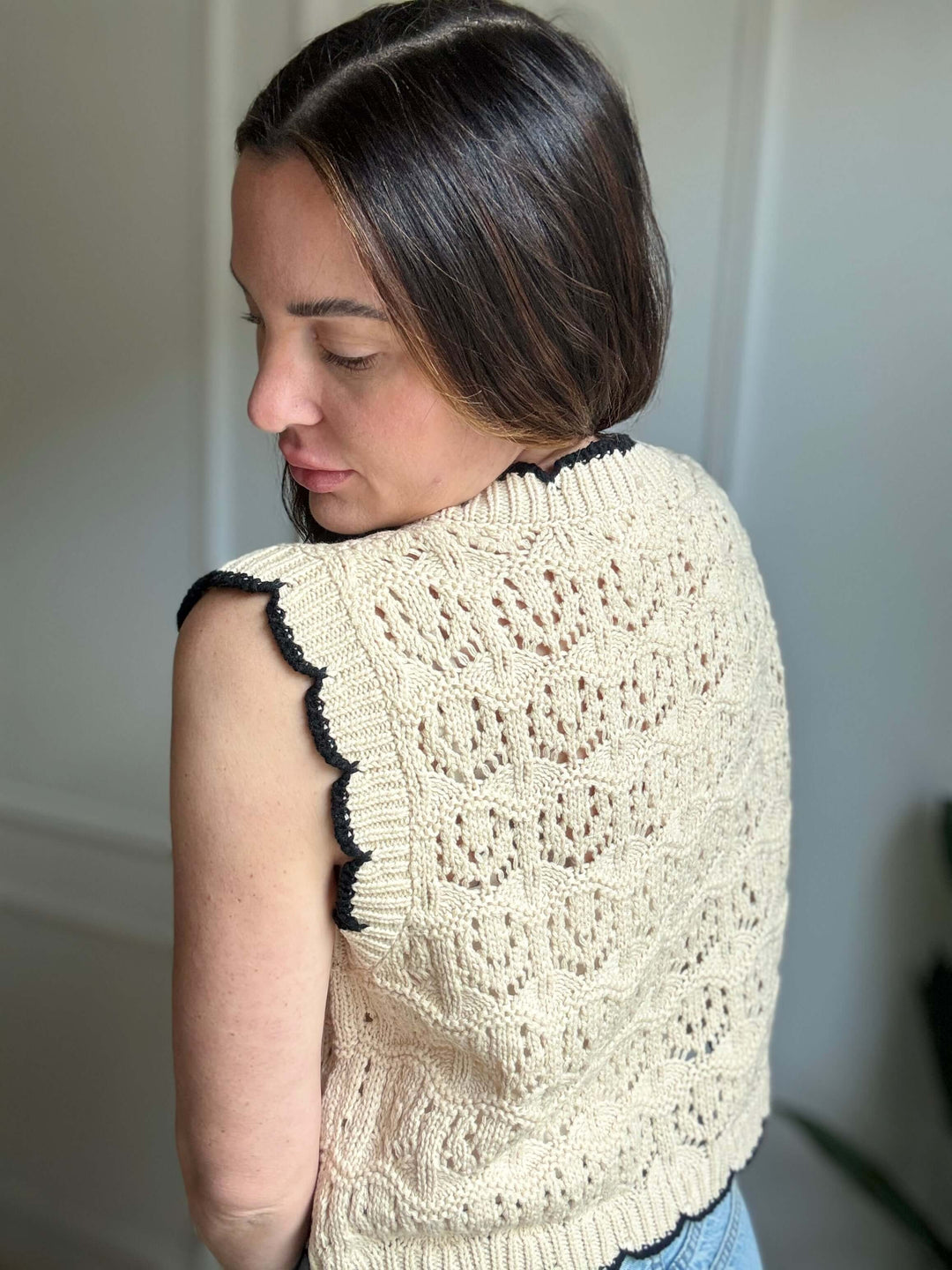 Woman modeling the Faithful Threads Crochet Sweater Vest with scallop edges and bow tie detail, showcasing elegant design.