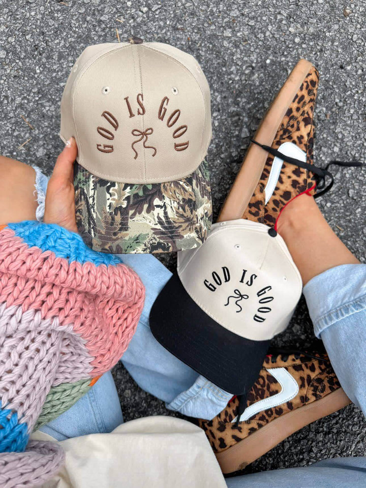 Two God Is Good caps in beige and camo, styled with a trendy outfit and trendy sneakers.