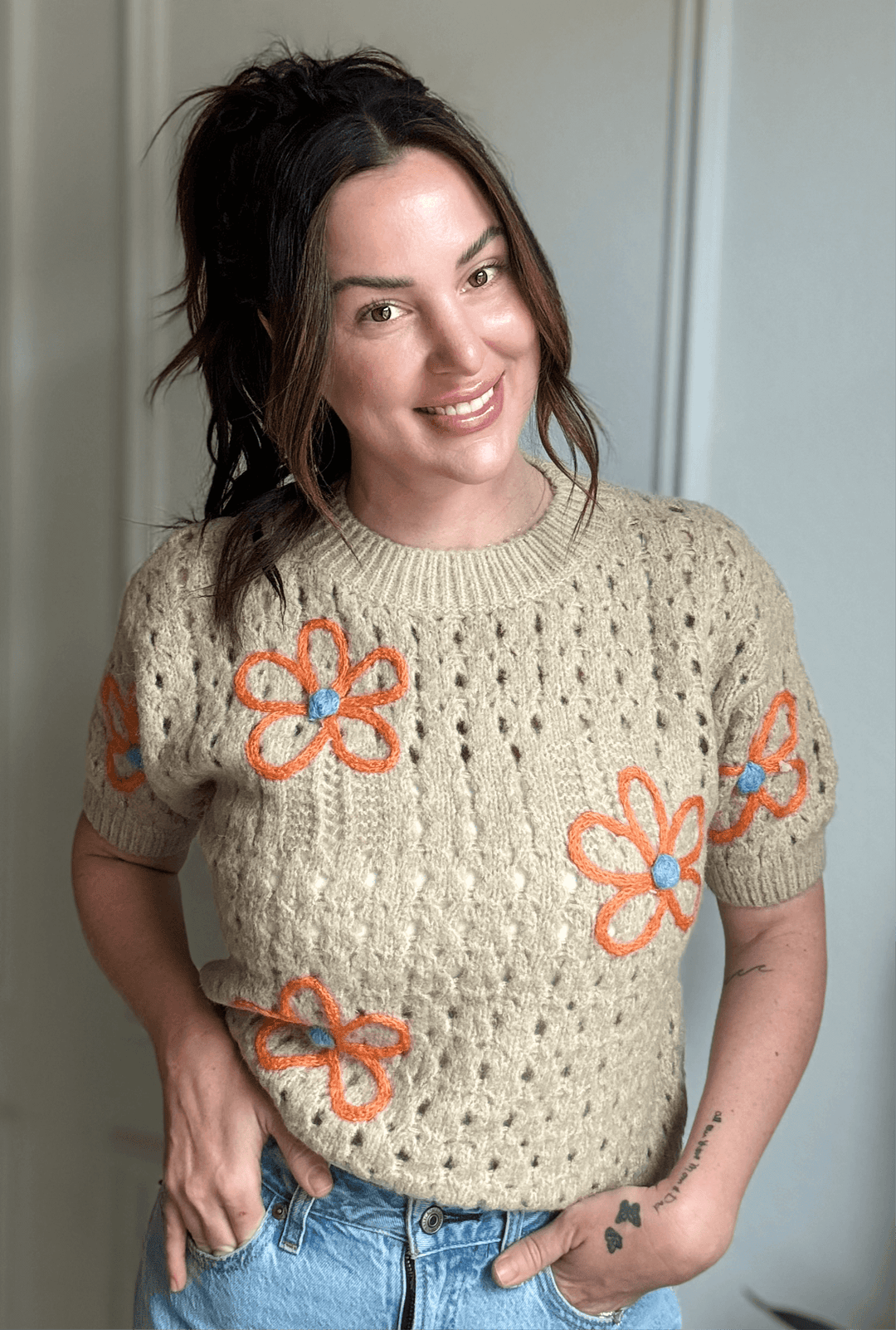 Smiling woman wearing the Graceful Bloom Sweater with floral embroidery, showcasing elegant knitwear for Christian women.