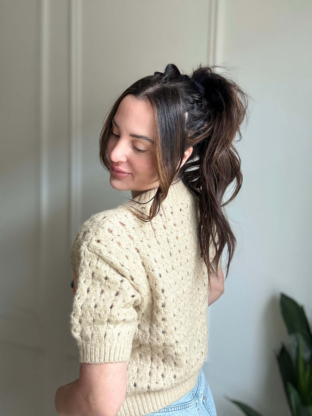 Woman wearing a Graceful Bloom Sweater, showcasing its cozy knit fabric and floral design in a soft neutral tone.