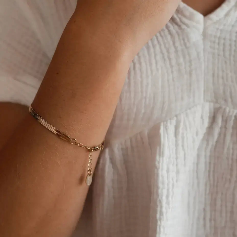 Close-up of Steadfast Love Bracelet on wrist, featuring 14kt gold-plated chain and engraved tag.